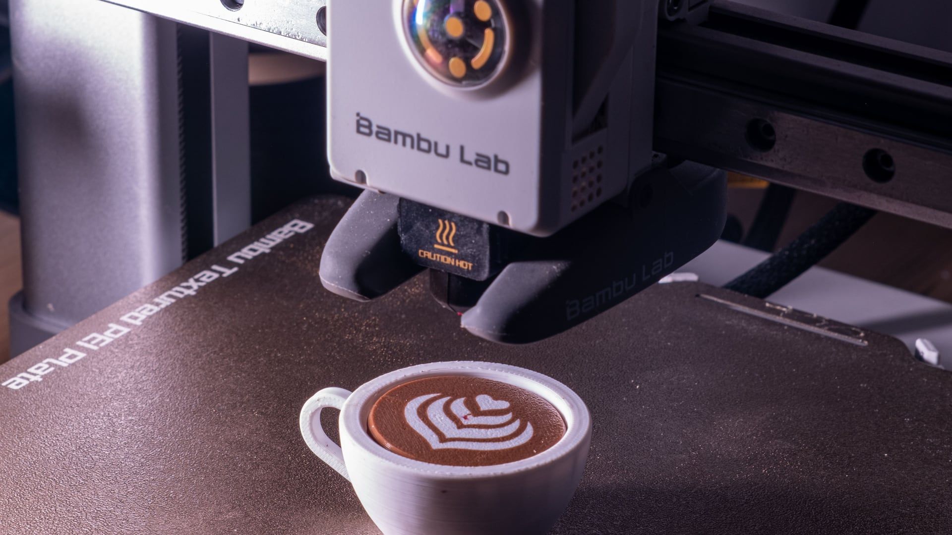 Printkop van een FDM-printer boven een 3D-geprint kopje cappuccino op het printbed